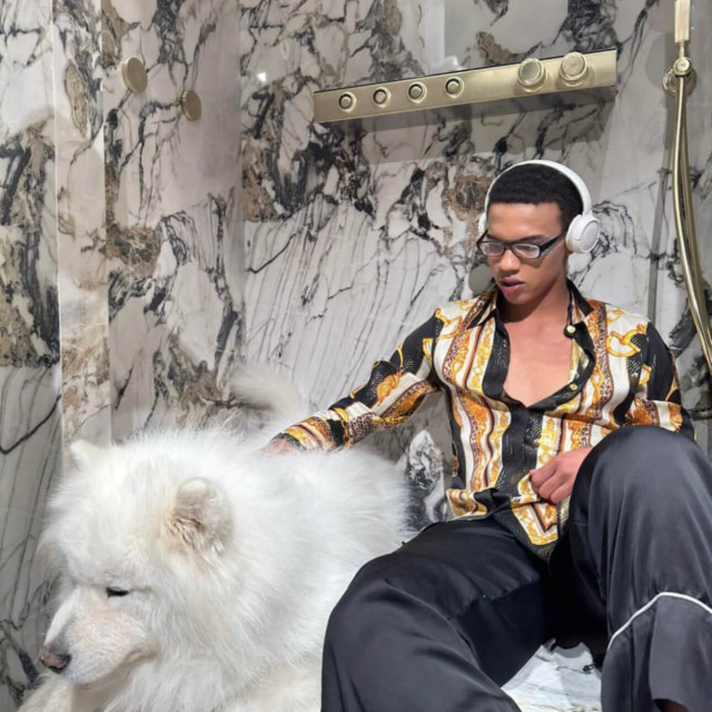 A man sits in a shower with a dog in the EURODOM bathroom equipment showroom