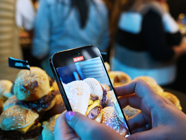 A guest at the opening of the SMASHER&CO restaurant takes photos of the burgers