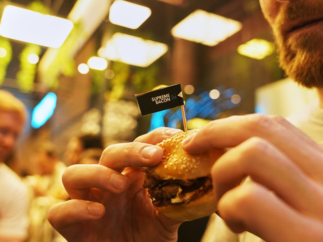 A guest holds a SMASH burger in his hands at the SMASHER&CO restaurant